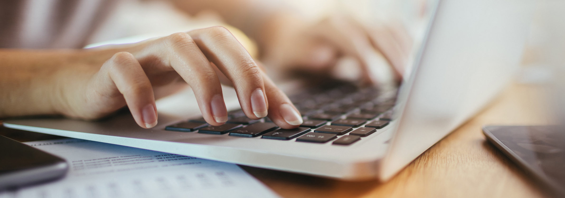 Close up of a employee using a laptop to help make Mergers and Acquisitions easier and the process smoother.